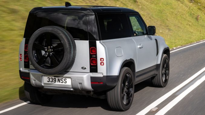 Ein silberner Land Rover Defender fährt 2021 auf einer britischen Landstraße.