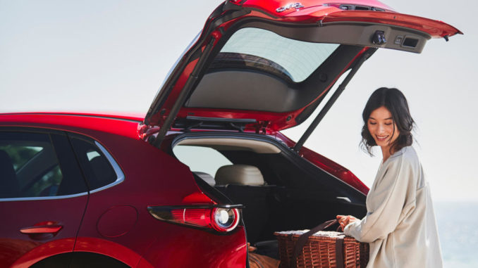 Die Fahrerin eines roten Mazda CX-30 lädt 2020 den Kofferraum aus.