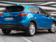 Ein blauer Mazda CX-5 steht 2012 auf einem Parkplatz vor einer bunten Plane.