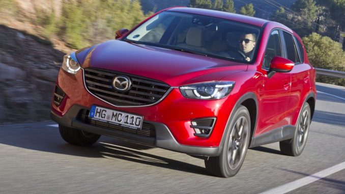 Ein roter Mazda CX-5 fährt 2015 auf einer Landstraße.