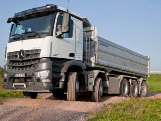 Ein weißer Mercedes-Benz Arocs 10x4/4 fährt auf hügeligem Gelände.