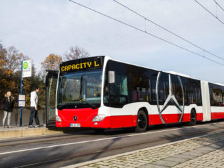 Ein rot-weißer Evobus Mercedes Capacity L steht 2014 an einer Haltestelle und lässt Fahrgäste vorne zusteigen