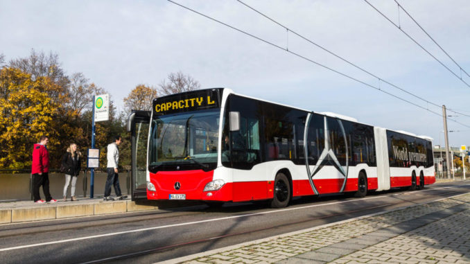 Ein rot-weißer Evobus Mercedes Capacity L steht 2014 an einer Haltestelle und lässt Fahrgäste vorne zusteigen