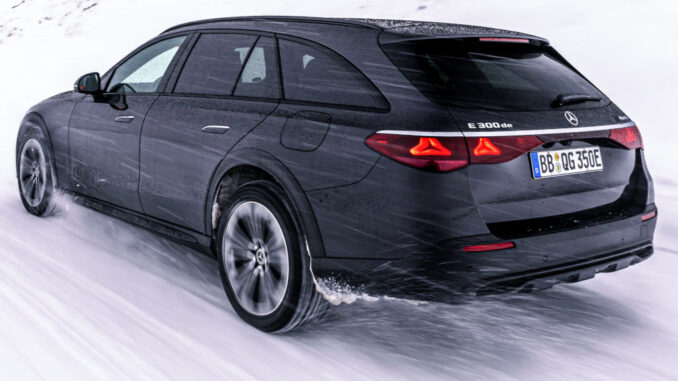 mercedes_e_klasse_t_2024 Ein schwarzer Mercedes-Benz E 300 de 4MATIC T-Modell All-Terrain mit EQ Hybrid Technologie fährt 2024 auf einer schneebedeckten Bergstraße.