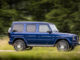 Ein Mercedes-Benz G 400 d; brilliant blau; Leder Nappa macchiatobeige/yachtblau, fährt 2019 auf einem Waldweg.