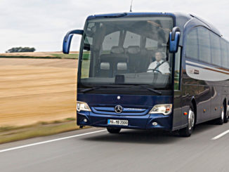 Ein blauer Mercedes Travego der Daimler-Tochter Evobus fährt an einem Weizenfeld vorbei.