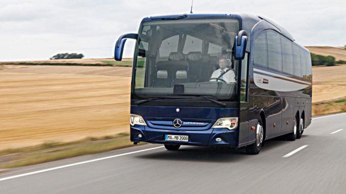 Ein blauer Mercedes Travego der Daimler-Tochter Evobus fährt an einem Weizenfeld vorbei.