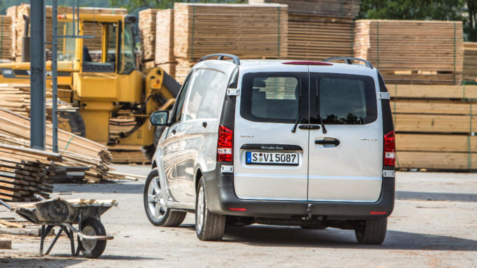 Ein silberner Mercedes Vito 116 CDI steht vor einem Holzstapel.