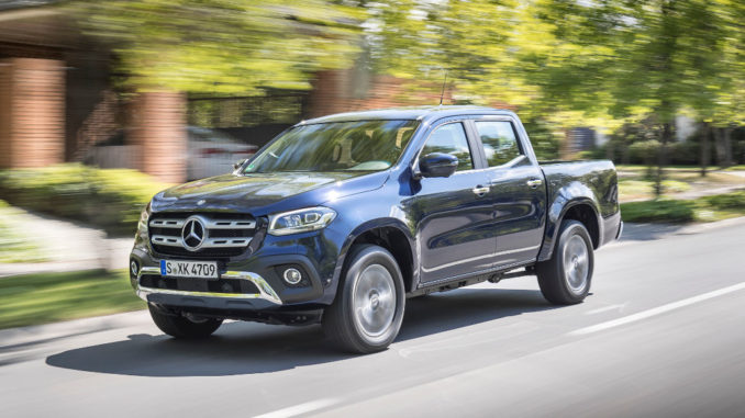 Eine blaue Mercedes X-Klasse Pick-Up fährt an einem Einfamilienhaus vorbei.