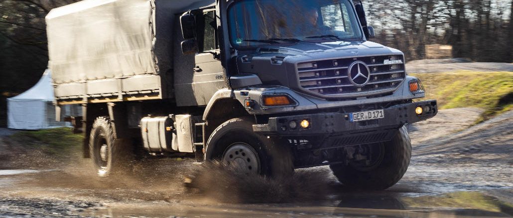 Ein silberner Mercedes Zetros fährt 2019 durch eine Schlammpfütze.