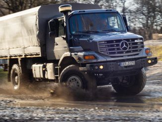 Ein silberner Mercedes Zetros fährt 2019 durch eine Schlammpfütze.