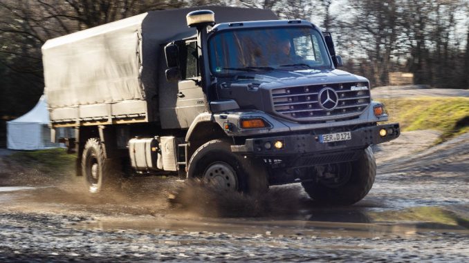 Ein silberner Mercedes Zetros fährt 2019 durch eine Schlammpfütze.