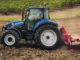 Ein blauer New Holland T5_115_ElectroCommand plügt einen Acker.