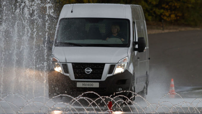 Ein silberner Nissan NV400 fährt bei einem Fahrsicherheitstraining über eine bewässerte Straße.