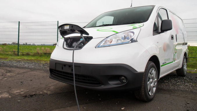 Ein weißer Nissan e-NV200 wird 2020 auf einem Betriebsgelände geladen.