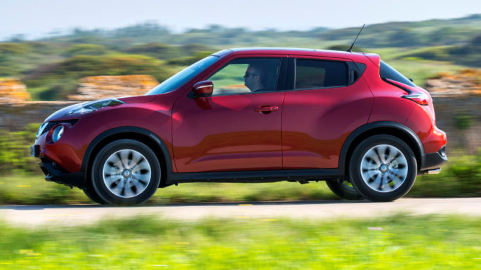 Ein roter Nissan Juke fährt 2014 auf einer Landstraße.