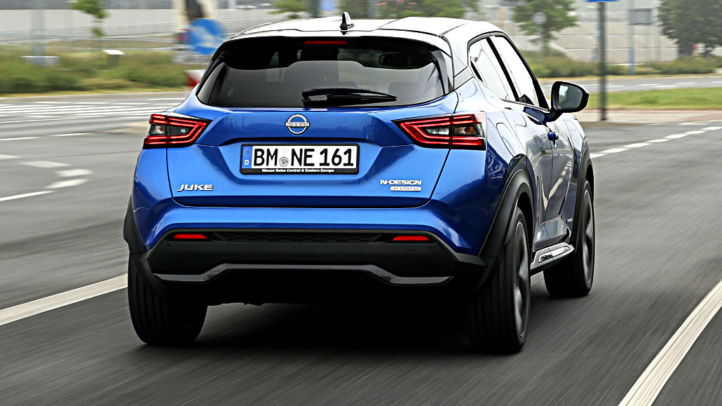 Ein blauer Nissan Juke HEV fährt 2022 durch eine Großstadt.