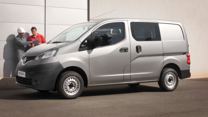 Ein grauer Nissan NV200 steht mit zwei Handwerkern auf einem Betriebshof.