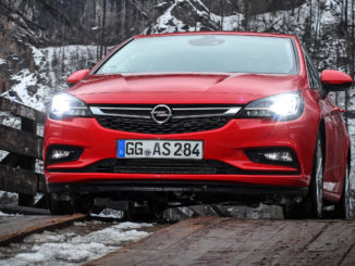 Ein roter Opel Astra K mit IntelliLux LED-Licht steht vor einer Felswand auf einer Holzbrücke.