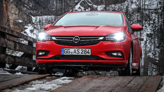 Ein roter Opel Astra K mit IntelliLux LED-Licht steht vor einer Felswand auf einer Holzbrücke.