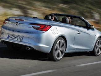 EIn silberner Opel Cascada fährt mit hoher Geschwindigkeit auf einer Landstraße.