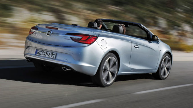 EIn silberner Opel Cascada fährt mit hoher Geschwindigkeit auf einer Landstraße.