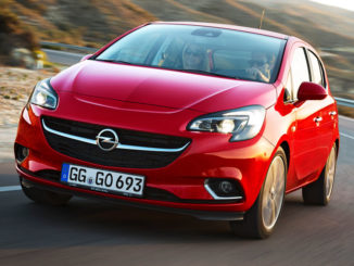 Ein roter Opel Corsa E fährt auf einer Landstraße durch eine mediterrane Landschaft.