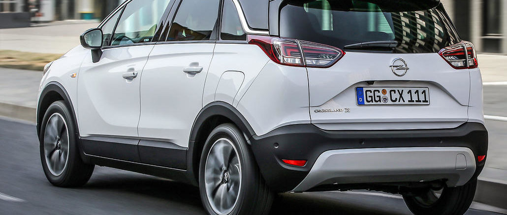 Ein weißer Opel Crossland X fährt durch die Straßen einer Stadt.