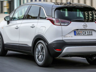 Ein weißer Opel Crossland X fährt durch die Straßen einer Stadt.