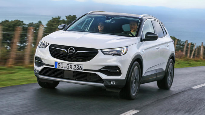 Ein weißer Opel Grandland X fährt an einem Weidezaun entlang.