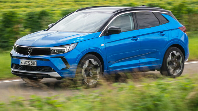 Ein blauer Opel Grandland fährt 2021 über eine Landstraße.