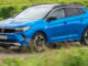 Ein blauer Opel Grandland fährt 2021 über eine Landstraße.