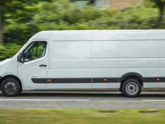 Ein weißer Opel Movano fährt an einer Hecke vorbei.