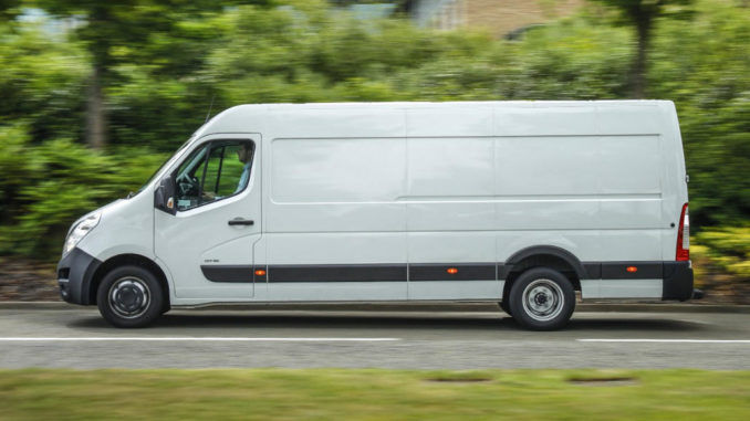 Ein weißer Opel Movano fährt an einer Hecke vorbei.