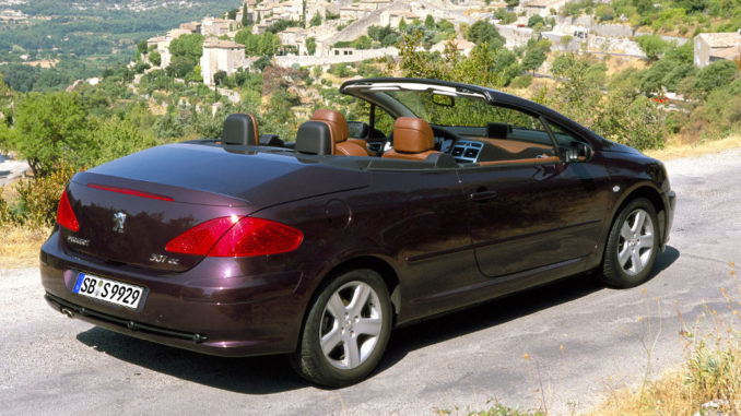 Ein lilafarbener Peugeot 307CC steht vor dem Panorama eines Bergdorfes.