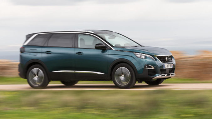 Ein grüner Peugeot 5008 fährt auf einer Landstraße.