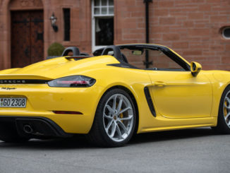 Ein Porsche 718 Spyder in racinggelb steht 2019 vor einem Schloss.