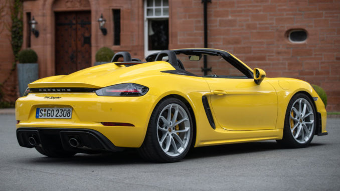 Ein Porsche 718 Spyder in racinggelb steht 2019 vor einem Schloss.