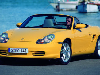 Ein gelber Porsche Boxster (986) steht vor einem Hafenbecken.