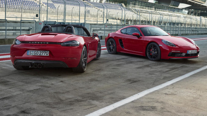 Zwei rote Porsche 718 Boxster und Cayman stehen in der Boxengasse einer Rennstrecke.