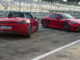 Zwei rote Porsche 718 Boxster und Cayman stehen in der Boxengasse einer Rennstrecke.