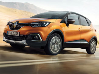 Ein orangener Renault Captur fährt durch eine karge Landschaft.