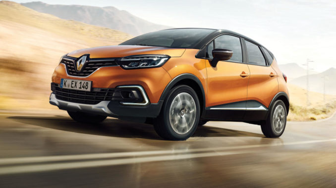 Ein orangener Renault Captur fährt durch eine karge Landschaft.