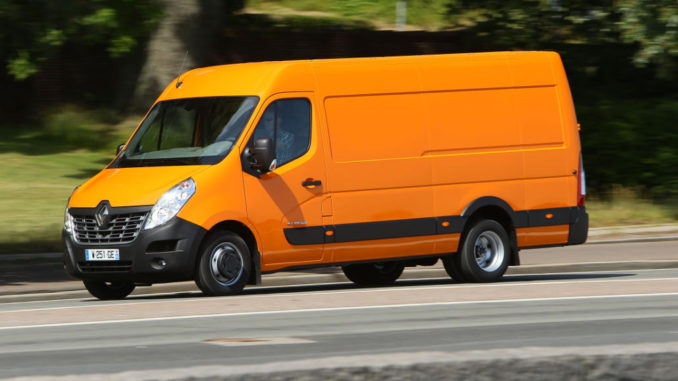 Ein orangener Renault Master fährt 2014 an einer Parkanlage entlang.
