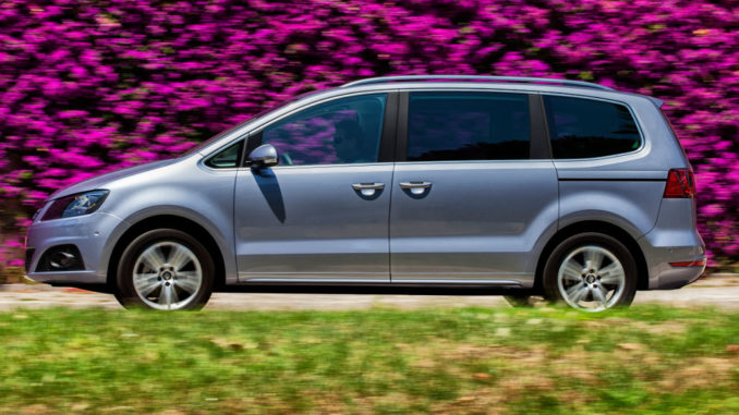 Ein silberner Seat Alhambra fährt 2015 an einer Blumenhecke vorbei.