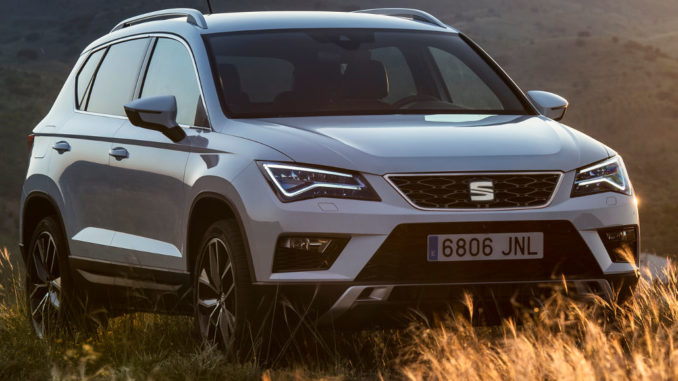 Ein weißer Seat Ateca steht im Abendlicht auf einer Wiese.