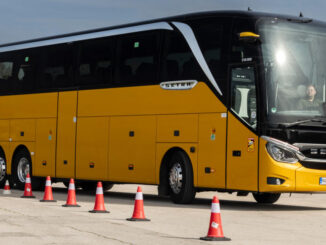 Gelber Setra TopClass S 516 HDH mit MirrorCam und 360° Kamerasystem, fährt 2024 auf einem Testgelände.