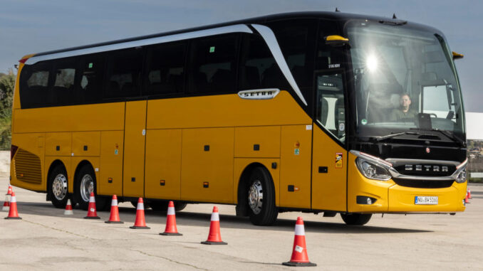 Gelber Setra TopClass S 516 HDH mit MirrorCam und 360° Kamerasystem, fährt 2024 auf einem Testgelände.