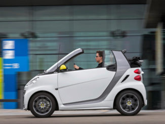 Ein weißes smart fortwo cabrio edition BoConcept, fährt 2013 vor einer Halle.