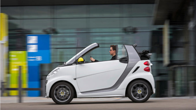 Ein weißes smart fortwo cabrio edition BoConcept, fährt 2013 vor einer Halle.